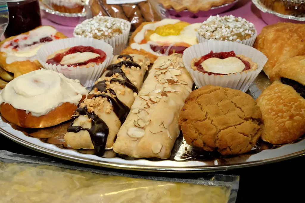 A plate of pastries and cookies on the table.